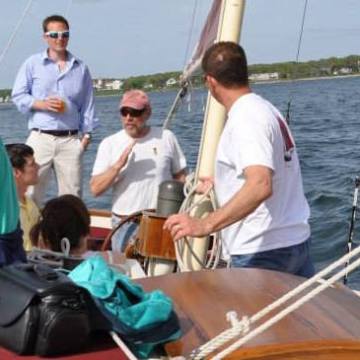 A crew member explains sailing techniques to a tour on the Pineapple Ketch.