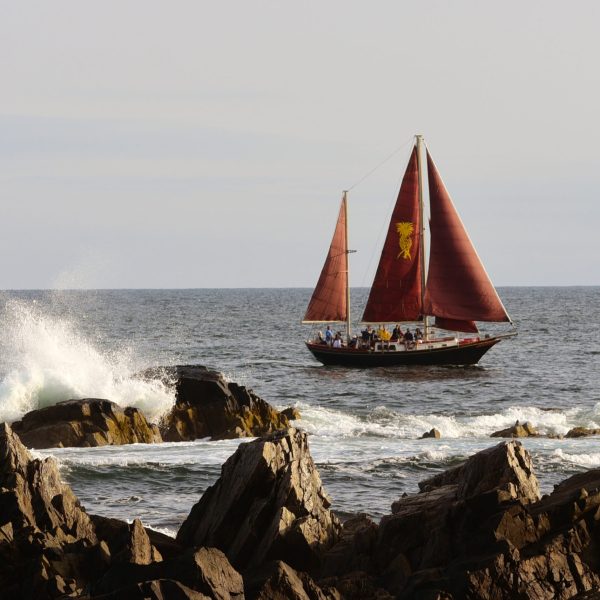 a boat floating on a rocky shore next to a body of water